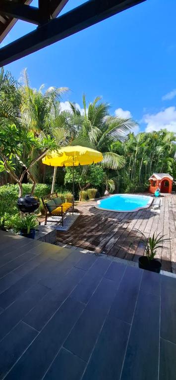a resort with a pool and a yellow umbrella at Villa Ulutawu in Le François