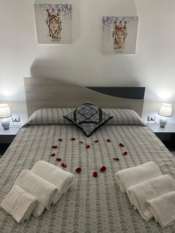 a bed with red rose petals on it at Momenti e Monumenti in Palermo