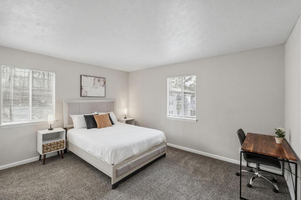 a bedroom with a bed and a desk and two windows at Cozy Downtown Stone Mountain Apartment in Stone Mountain
