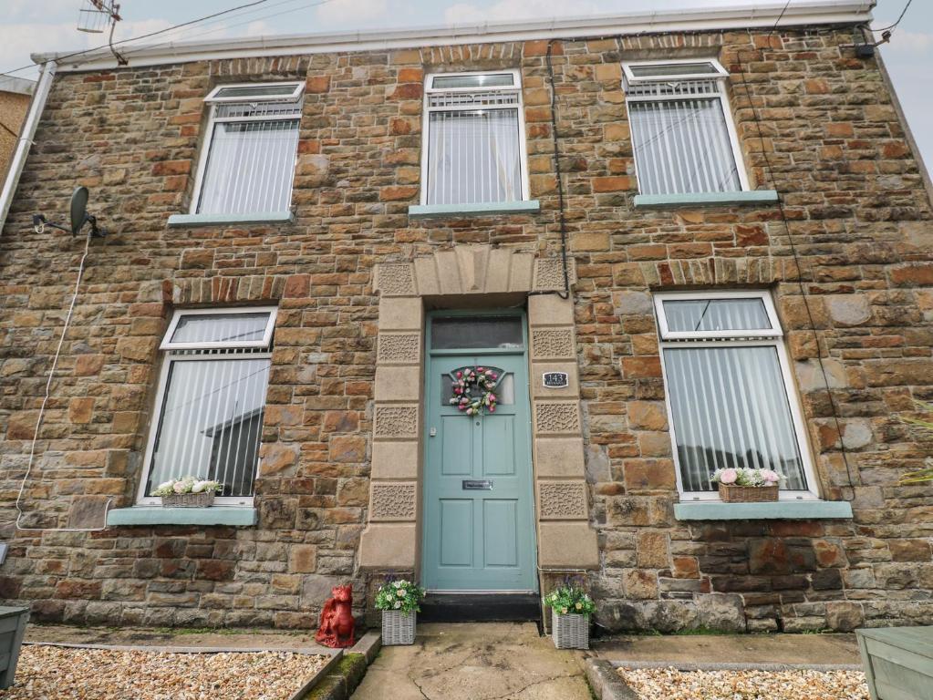 a brick house with a blue door and windows at Brynawel in Burry Port