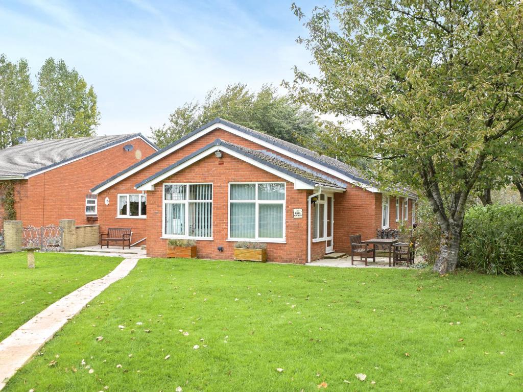 a red brick house with a picnic table in a yard at Quail Cottage - Uk50659 in Little Singleton