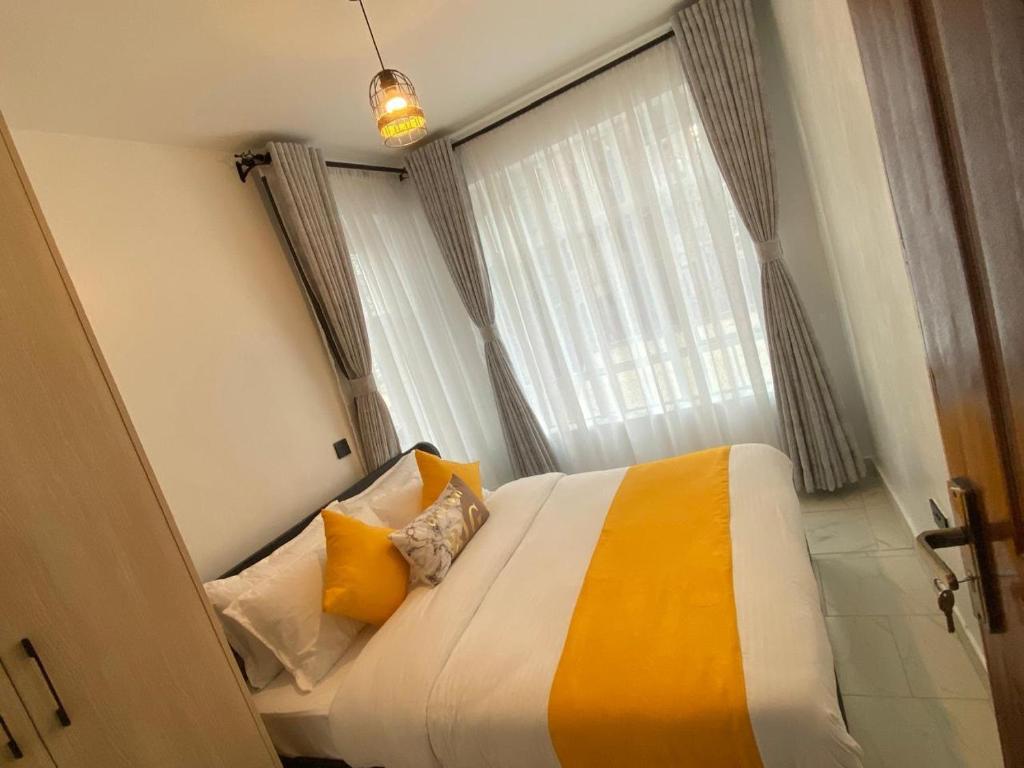 a bedroom with a bed with yellow pillows and a window at Urbanza Haven Nakuru in Nakuru