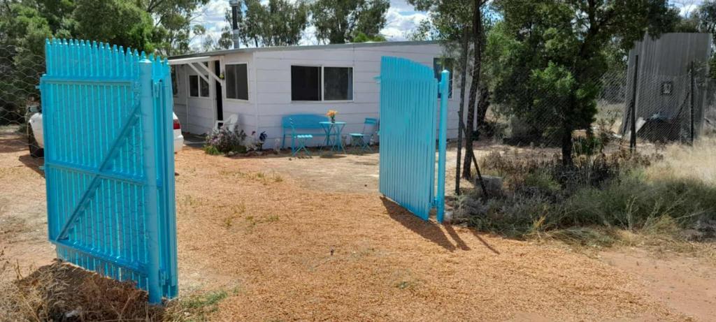 a blue gate in front of a trailer at Blue Flower Cottage in Lightning Ridge