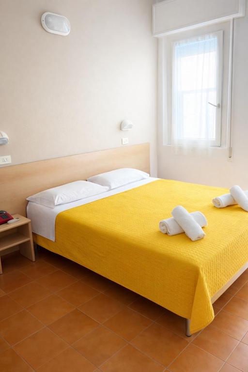 sypialnia z żółtym łóżkiem i ręcznikami na nim w obiekcie Hotel Adria Mare w Rimini
