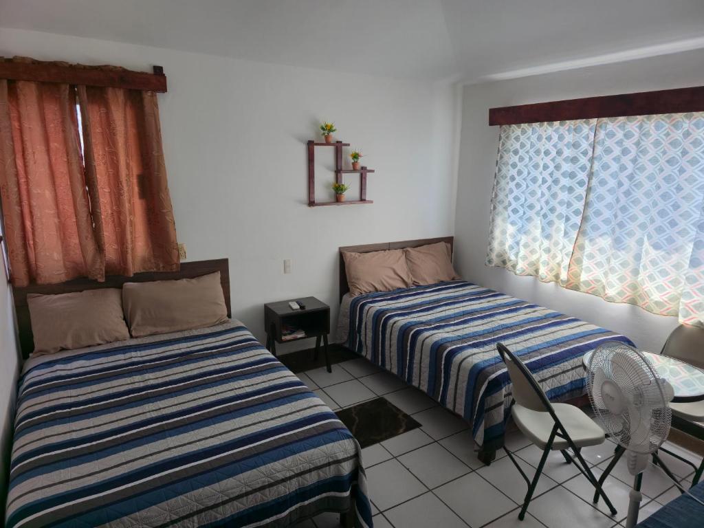 a bedroom with two beds and a chair in it at Cómoda habitación Mar in Veracruz