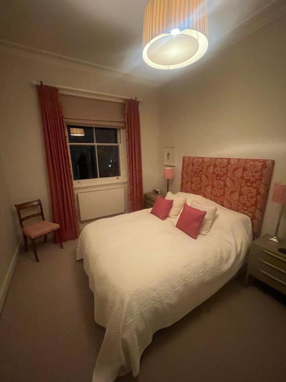 a bedroom with a large white bed with red pillows at Hampstead Residence Hotel in London