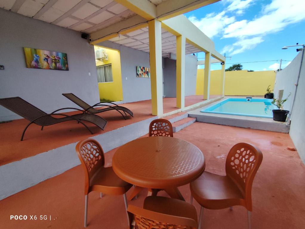 a patio with a table and chairs and a pool at Casa Mineira - Flats novos em Ponta de Mangue - Maragogi in Maragogi