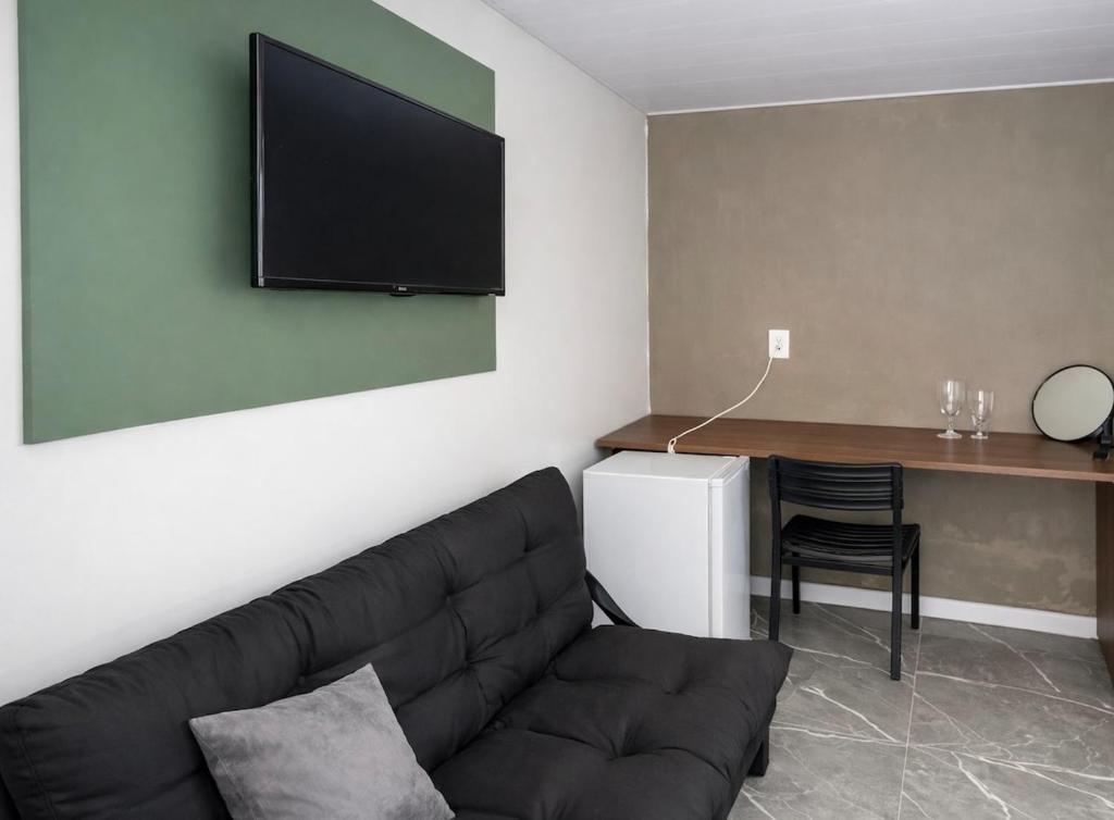 a living room with a couch and a television on the wall at Apartamento com Custo Benefício Imbatível in Passo Fundo