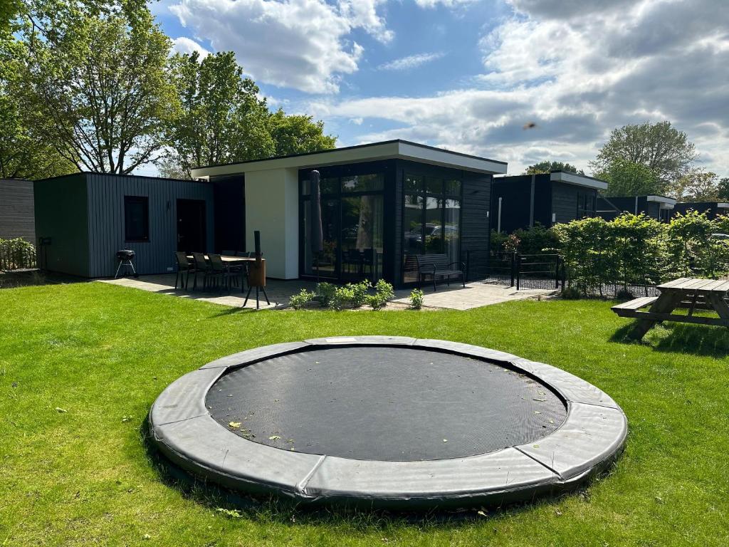 a trampoline in the grass in front of a house at Bad Hoophuizen Chalet L-Cube 6 Nr Eik 19 in Hulshorst