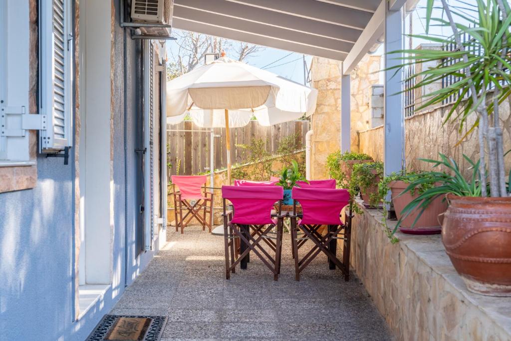 two pink chairs and an umbrella on a patio at Casa Carina in Lakíthra