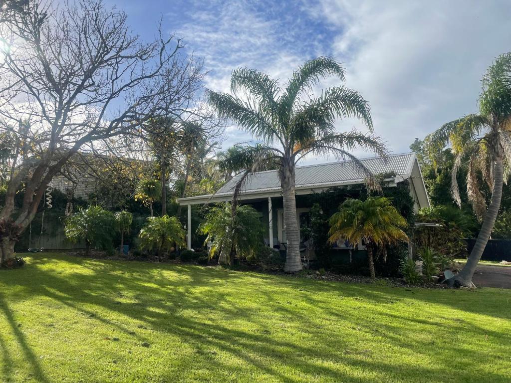 a house with palm trees in front of a yard at Bosuns Locker in Auckland