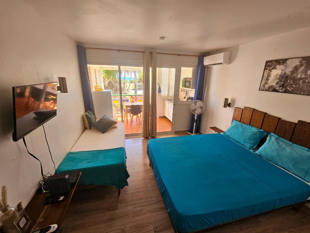 a bedroom with two beds and a television and a balcony at COZY Studio 331 ADR in Saint-François