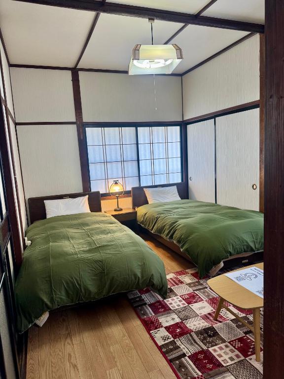 a bedroom with two beds and a table with a lamp at ANFT-shiro in Azumino