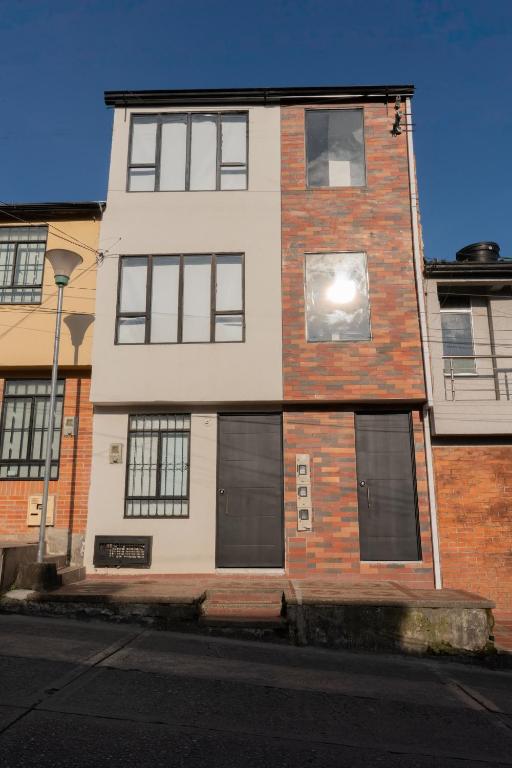 a tall brick building with windows on a street at Denier House Fuente de los Rosales - A 5 minutos de Centros Comerciales in Ibagué