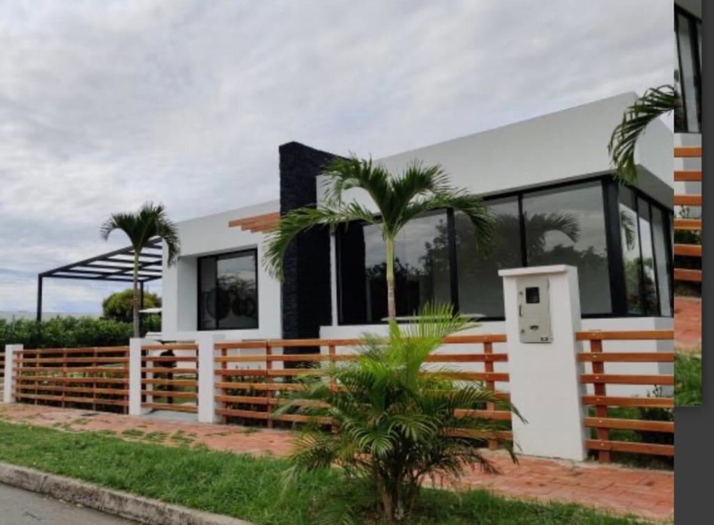 a house with a fence and palm trees in front of it at Espectacular Casa Quinta in Girardot