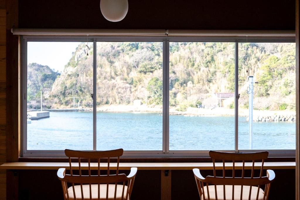 two chairs sitting in front of a window looking out at the water at Kaitan雲津 in Matsue