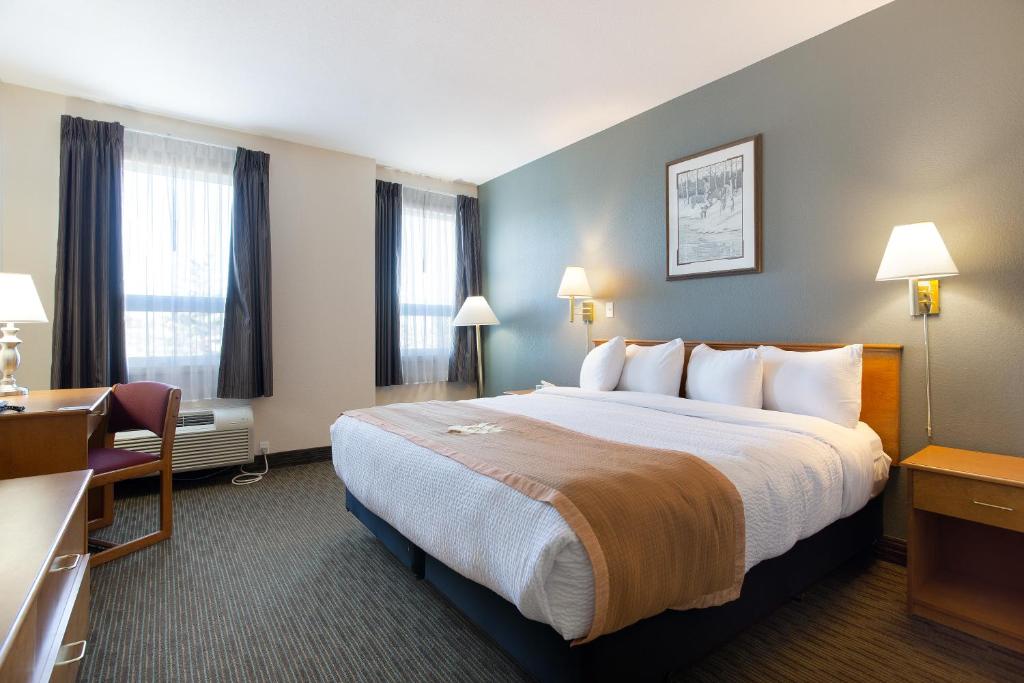 a hotel room with a large bed and windows at Lakeview Inns & Suites - Okotoks in Okotoks
