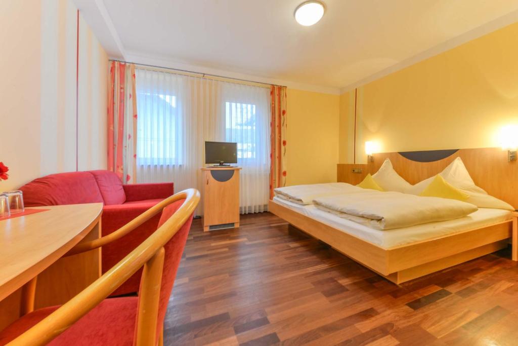 a bedroom with a bed and a couch and a table at Hotel Peterhof in Dietenheim