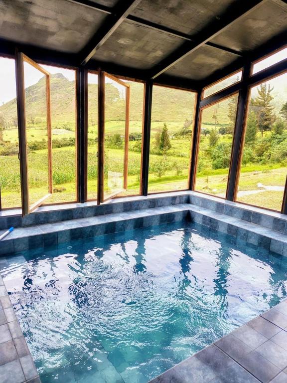 a swimming pool in a house with windows at Domo Fengari in Pululahua