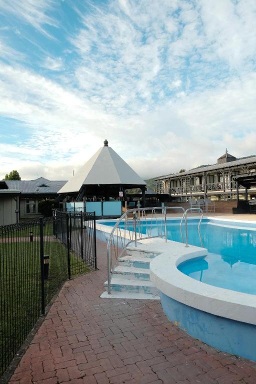 a swimming pool with a large umbrella next to a building at Tokaanu Retreat in Turangi