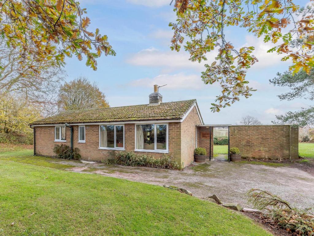 a brick house with a driveway in a yard at Hall Farm Bungalow in Shirley