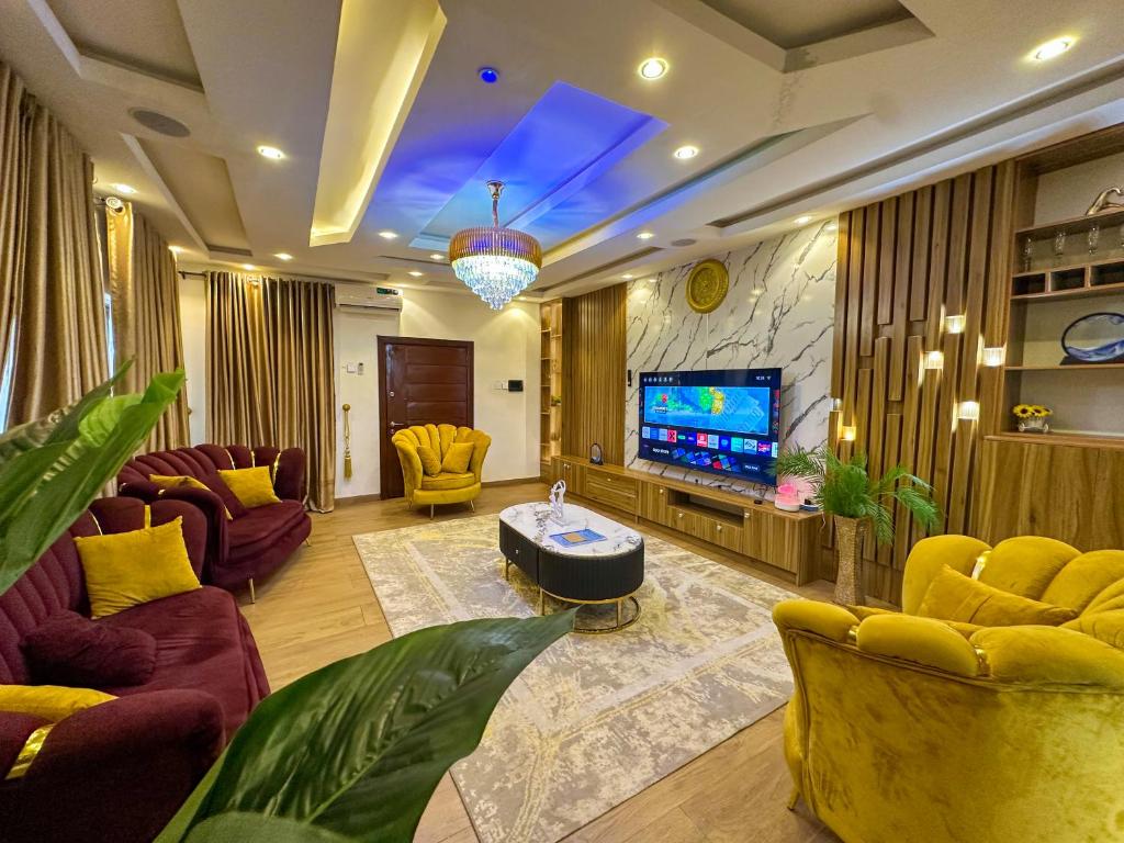 a living room with yellow furniture and a flat screen tv at Engeemos Bookastay Apartments in Abeokuta