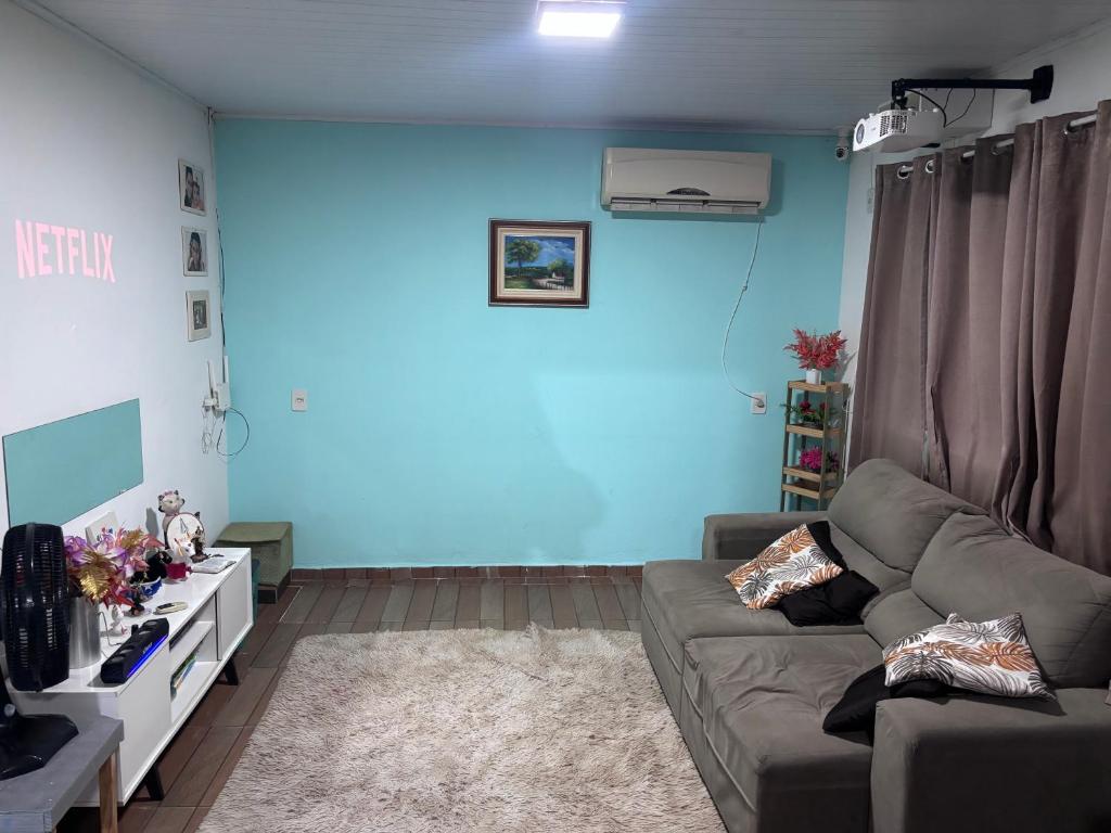 a living room with a couch and a blue wall at Praia do sonho, Quarto para até 4 pessoas super aconchegante in Palhoça