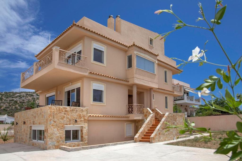 a large house with a staircase in front of it at Lagonisi Beach Villa in Lagonissi