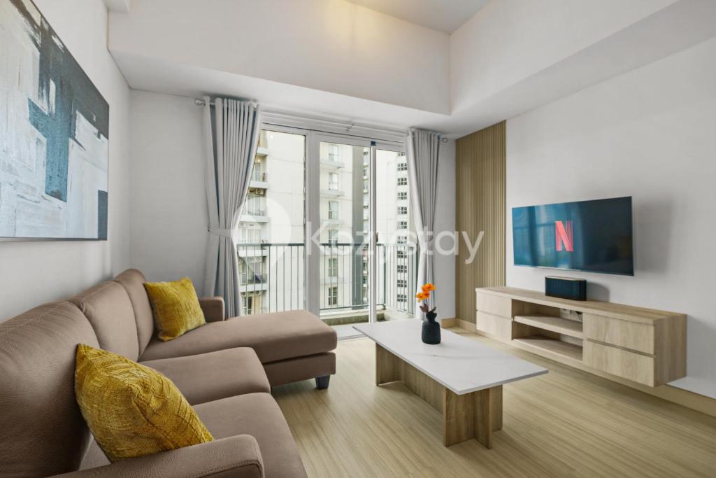 a living room with a couch and a tv at Elion by Kozystay - BSD in Samporo