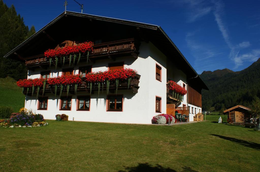ein Gebäude mit roten Blumen auf den Balkonen in der Unterkunft Saxerhof in Schmirn