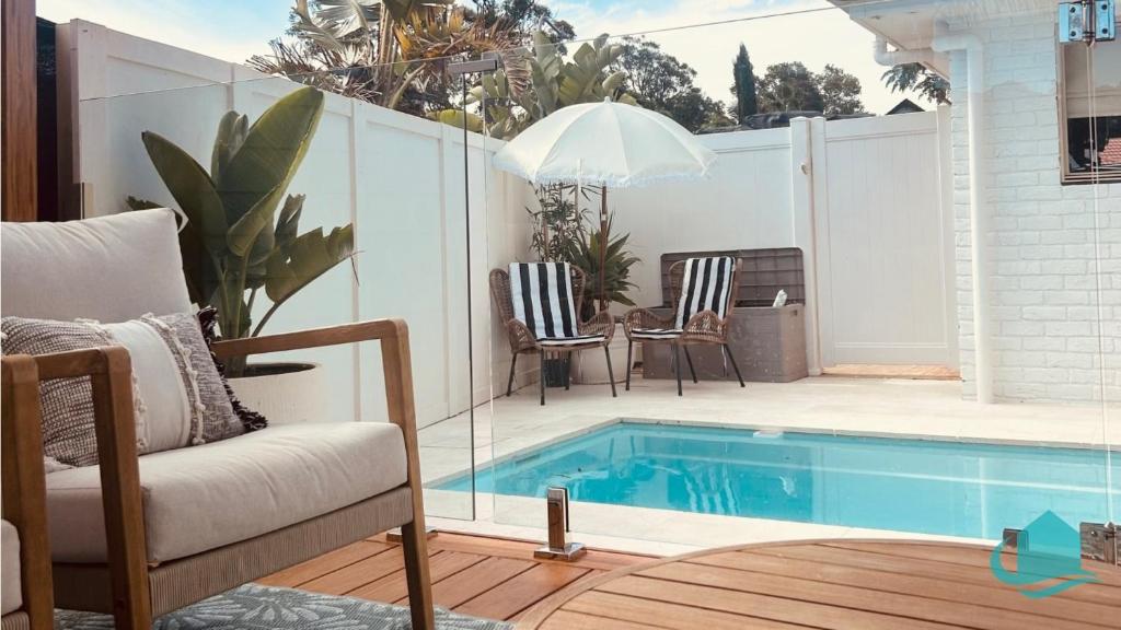 a patio with a swimming pool with chairs and a table at Summerland Escape in Summerland Point