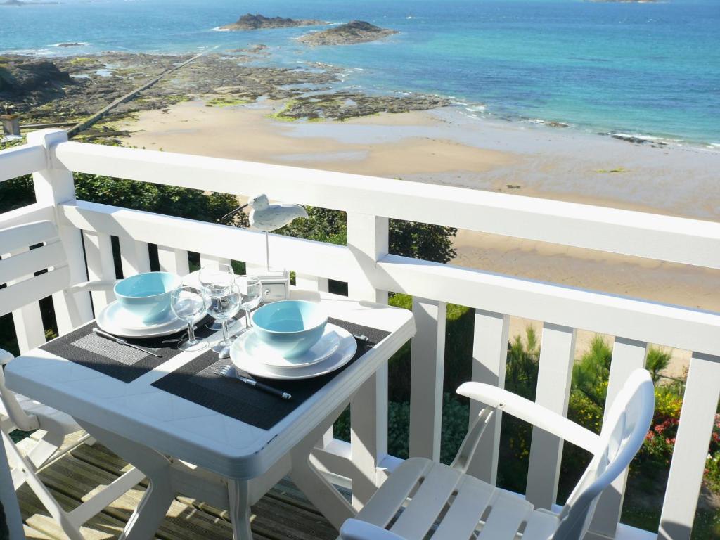 une table et des chaises sur un balcon avec vue sur la plage dans l'établissement Appartement ROCK WILL, à Dinard