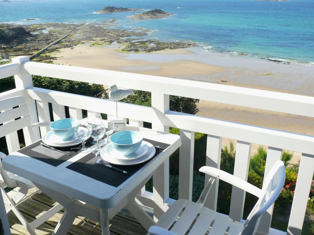 uma mesa e cadeiras numa varanda com vista para a praia em Appartement ROCK WILL em Dinard