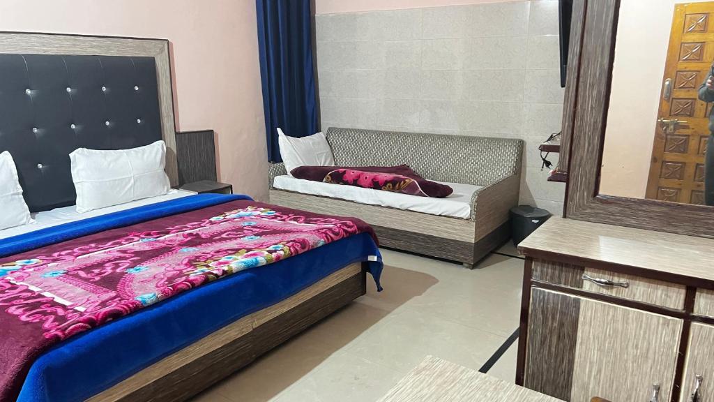 a bedroom with a bed and a mirror and a couch at Krishna Holiday Guest House in Dharmsāla
