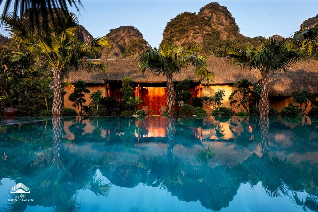 a resort with palm trees and a swimming pool at The Bổi Heritage Tam Coc in Ninh Binh