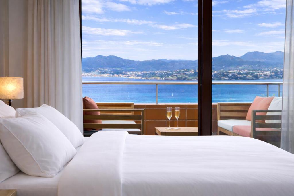 a hotel room with a bed and a large window at Holibai, Son do mar apto con terraza y vistas a la bahia de Baiona in Baiona