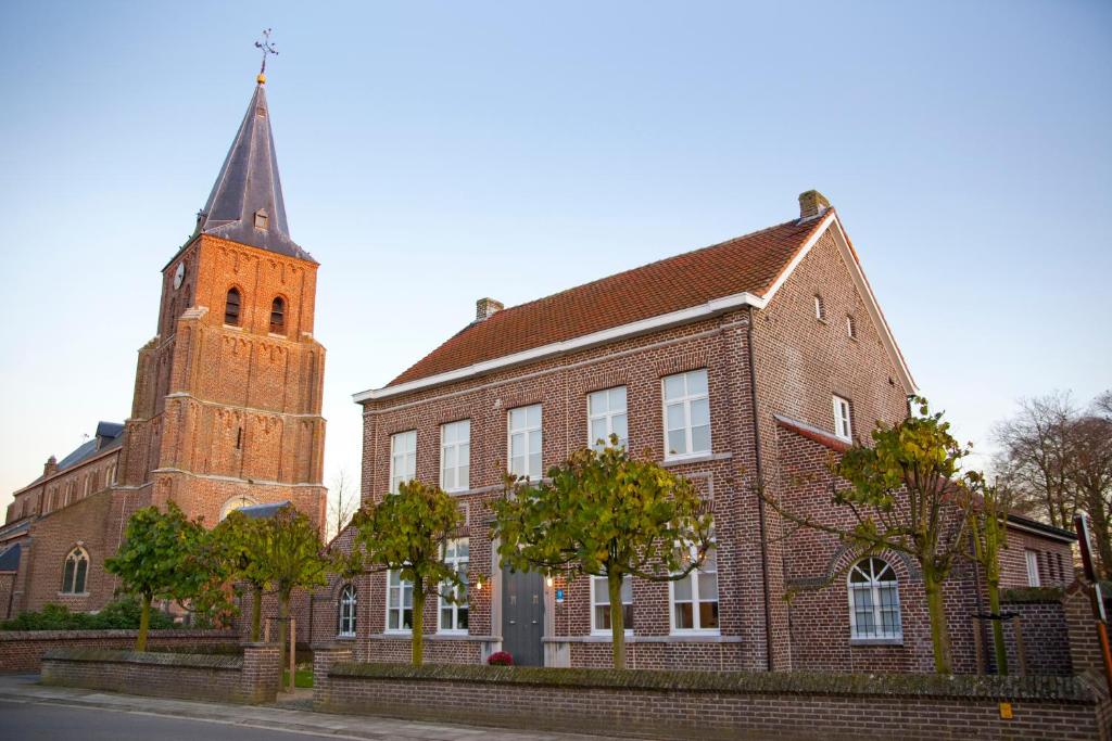 a church with a tower and a brick building at De Pastory in Grote-Brogel