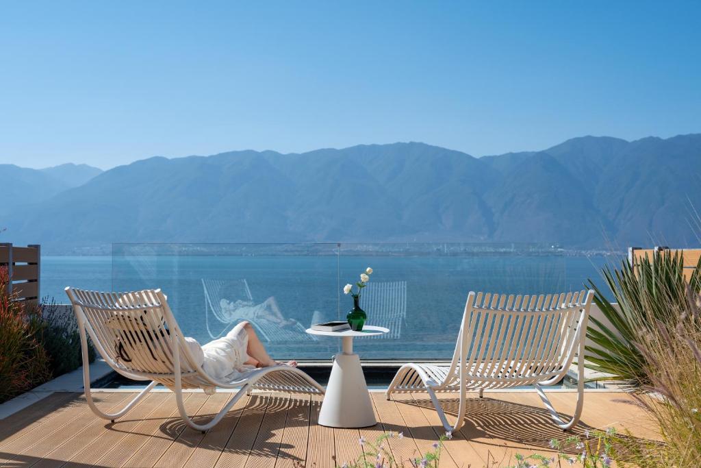 two chairs and a table with a woman sitting on it at Dali Shuanglang Erhai Lake in Dali Shuanglang