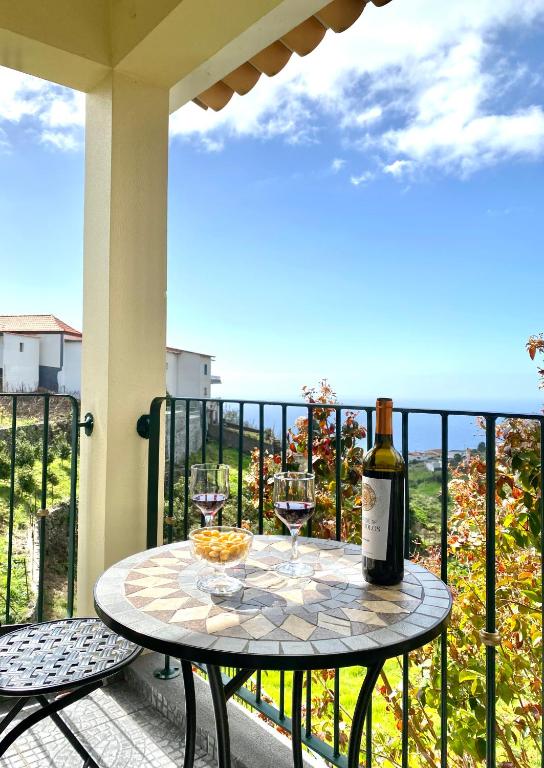 a table with two glasses of wine on a balcony at "Fifi House" in Estreito da Calheta