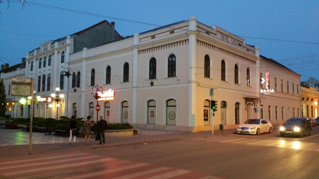 een groot wit gebouw in een stadsstraat 's nachts bij Hotel Dacia in Lugoj