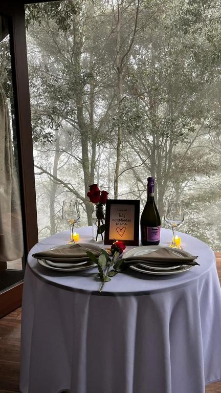 a table with a white table cloth and a bottle of wine at Cabaña Sendero De Las Luciernagas in Zacatlán