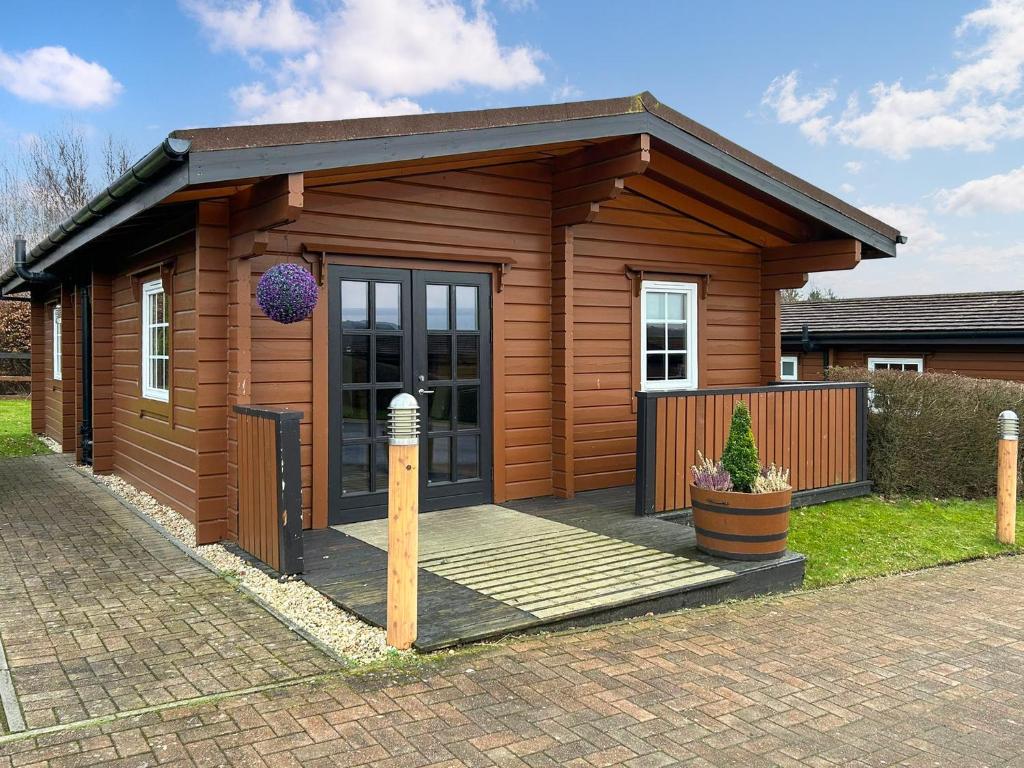 a small wooden cabin with a porch in a yard at Lodge 2 - Uk51263 in Glasgow