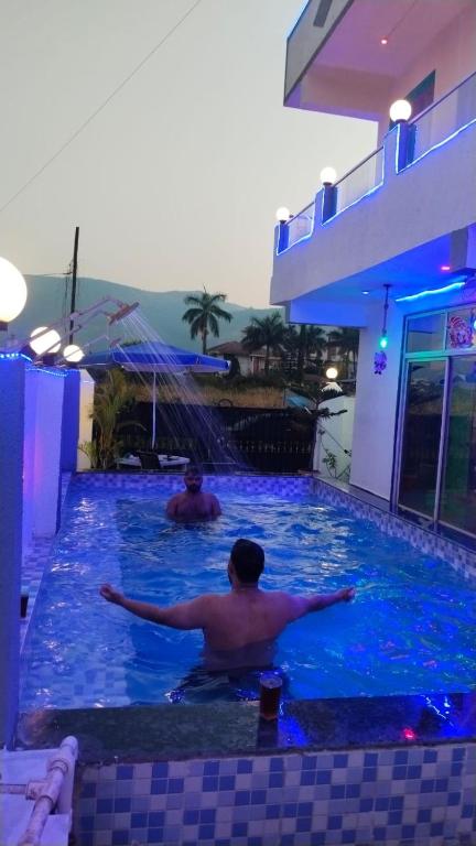 two men are swimming in a swimming pool at Lonavala Golden Bird 3 bhk villa in Malavli
