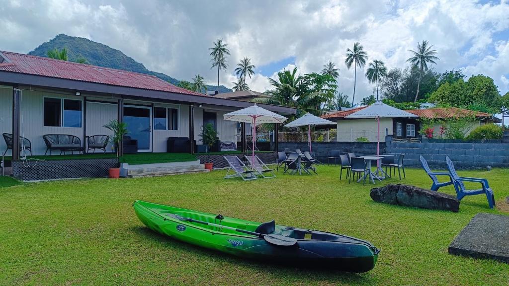 a green kayak on the grass in front of a house at Hava'e Lodge TEAHUPOO in Teahupoo