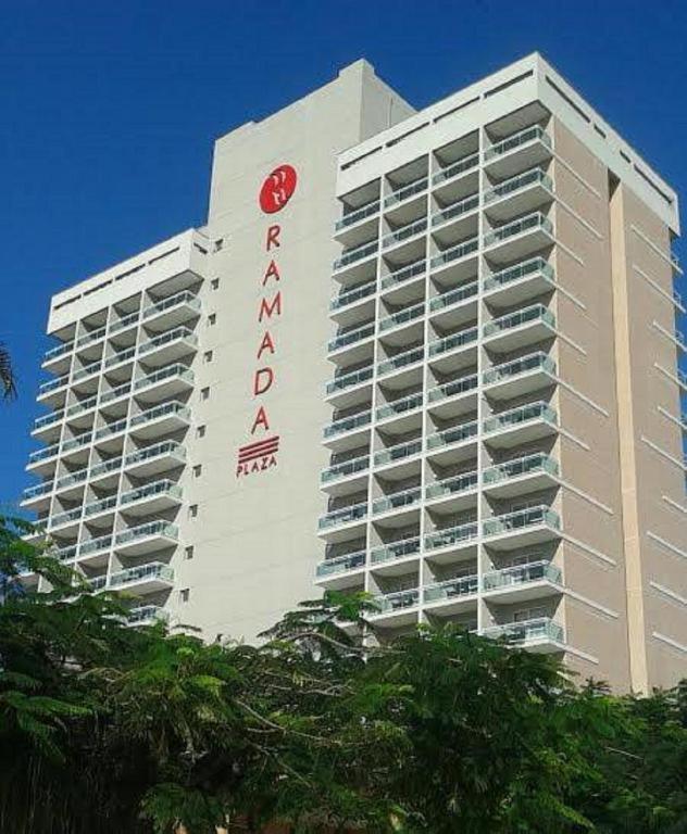 Un gran edificio blanco con un cartel rojo. en Flat Macaé, en Macaé