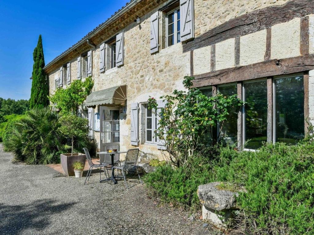 a brick building with a table and chairs in front of it at Logis Hôtel La Ferme de Flaran in Maignaut