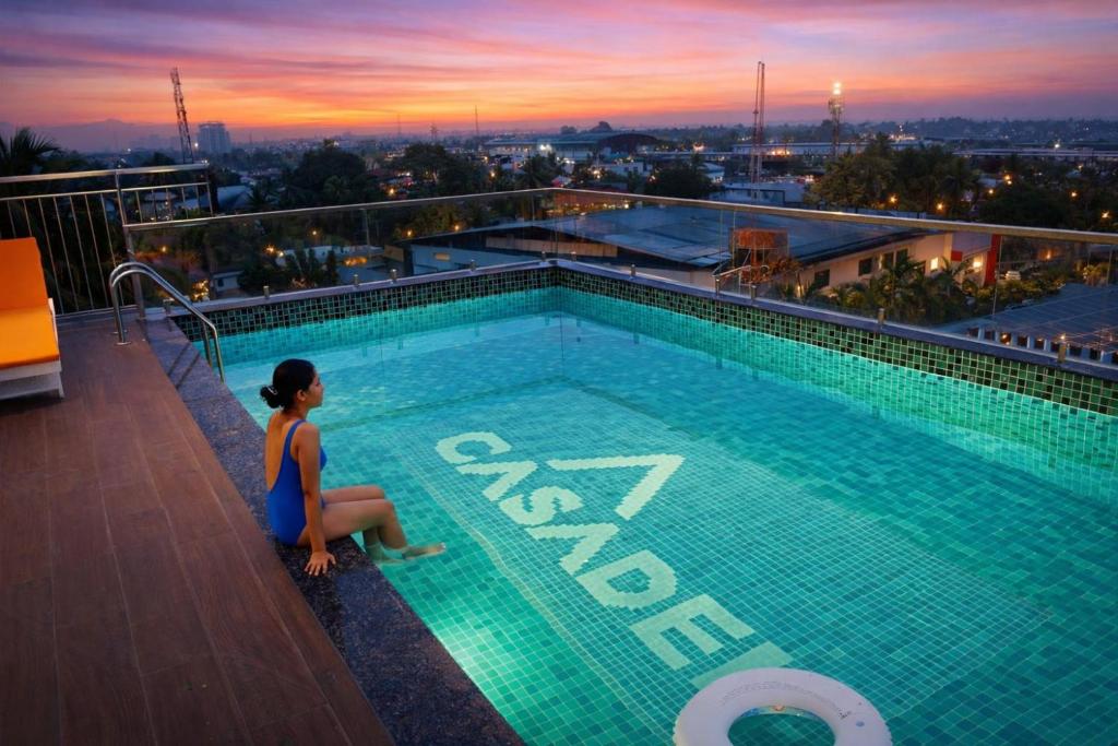 a woman sitting next to a swimming pool on top of a building at Hotel Hanata Kochi in Cochin