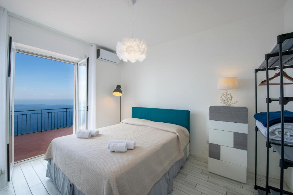 a bedroom with a bed and a balcony with the ocean at VivimiHome - Casa Tiberio in Conca dei Marini