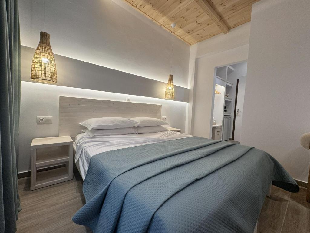 a bedroom with a bed with a blue blanket at Patras Rooms est 1990 in Fournoi