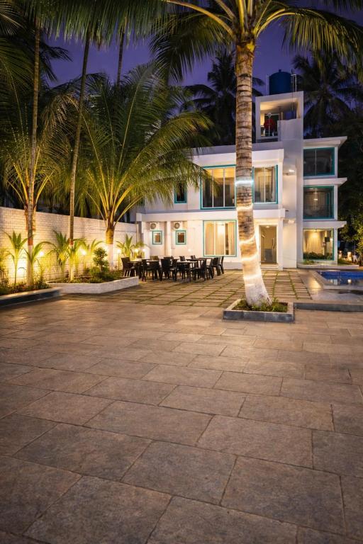 a large white building with palm trees in front of it at Bellevue Retreat in Alībāg